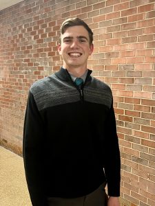 David Koster smiling in front of a brick wall