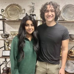 Hina Shehzad and Ephraim Bennett in front of trophies on shelves