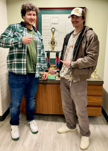 Tony Miklovis and Blaine Montford standing in front of trophies holding a large trophy