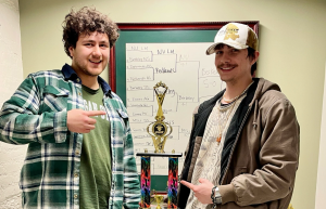 Tony Miklovis and Blaine Montford standing in front of trophies holding a large trophy