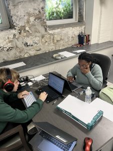 Glen Scully and Zaria Jarman sitting at a desk working on laptops