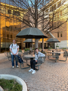 Stephen Lewis and Joanna Gusis outside at a table with an umbrella