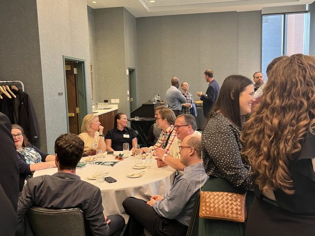 Group at a reception where some people are seated and some are standing talking