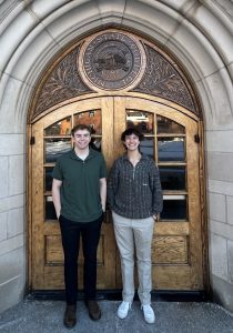 Stephen Lewis and Joanna Gusis standing outside in front of an ornately carved wooden door