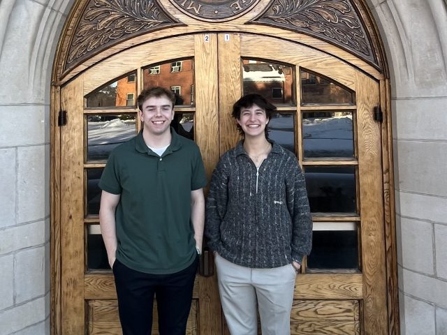 Stephen Lewis and Joanna Gusis standing outside in front of an ornately carved wooden door