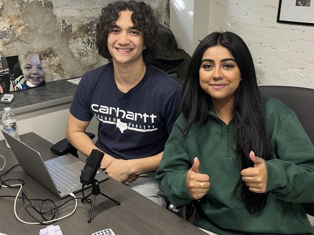 Ephraim Bennett and Hina Shehzad seated at a desk doing thumbs up