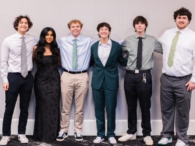 Group photo of students competing at the NDT standing with their arms around each other