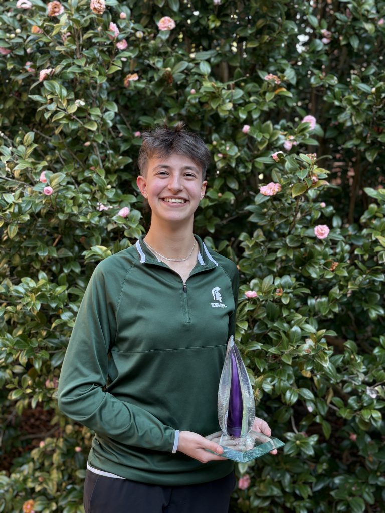 Joanna Gusis pictured in front of a flowering shrub with a flame-like glass trophy