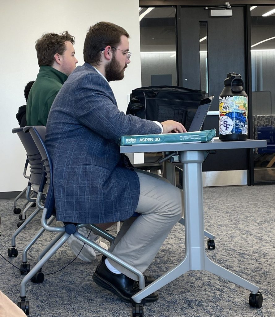 Balin and Jack seated behind table in debate round
